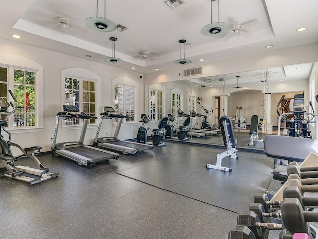 workout area with ceiling fan and a raised ceiling