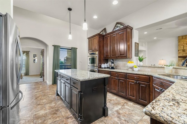 504 Pheasant Mdw, Liberty Hill, TX 78642 - kitchen featuring stainless steel appliances, a sink, arched walkways, tasteful backsplash, and pendant lighting