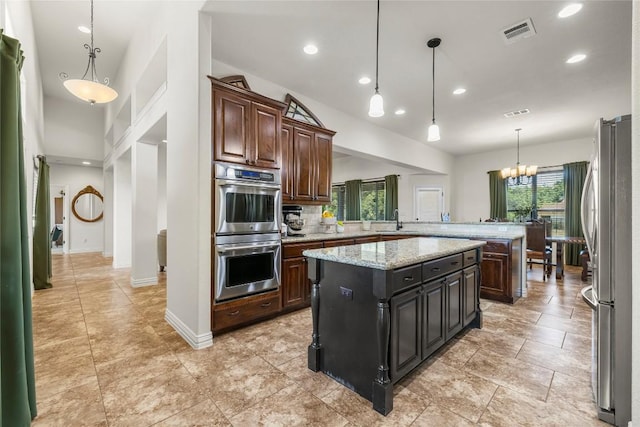 504 Pheasant Mdw, Liberty Hill, TX 78642 - kitchen with appliances with stainless steel finishes, a sink, a peninsula, a chandelier, and a center island