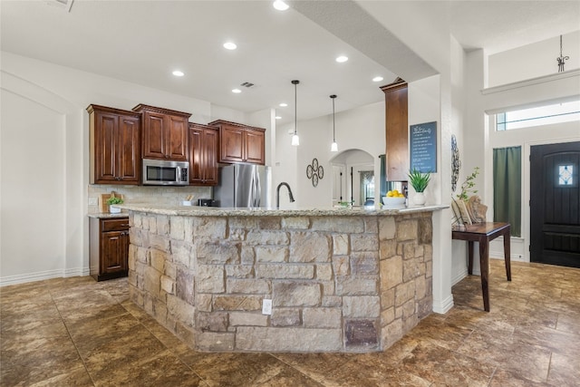 kitchen featuring arched walkways, visible vents, a kitchen breakfast bar, light countertops, and appliances with stainless steel finishes