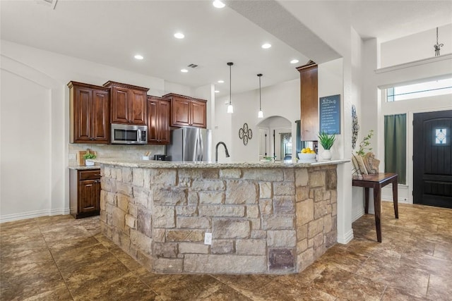 504 Pheasant Mdw, Liberty Hill, TX 78642 - kitchen with appliances with stainless steel finishes, arched walkways, tasteful backsplash, recessed lighting, and hanging light fixtures