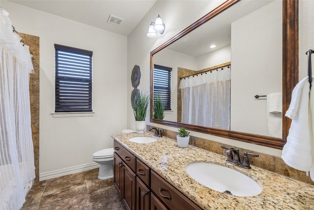 full bath featuring toilet, double vanity, visible vents, and a sink