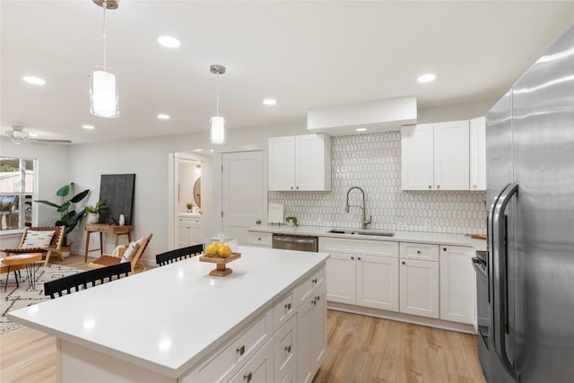 kitchen featuring a sink, white cabinetry, stainless steel appliances, light countertops, and decorative backsplash