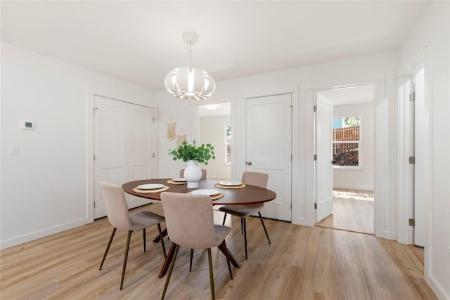 dining space featuring a notable chandelier, baseboards, and light wood-style floors