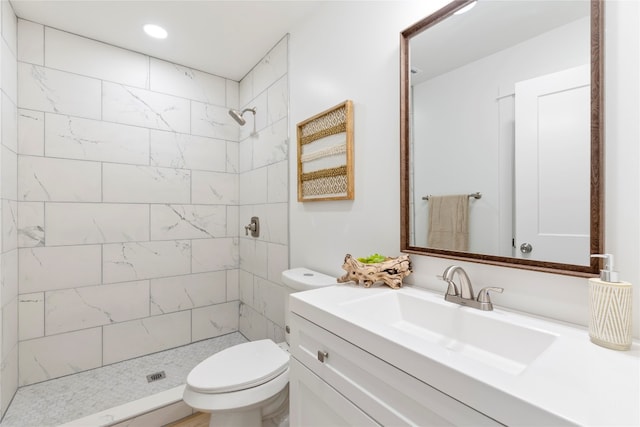 bathroom with tiled shower, vanity, and toilet