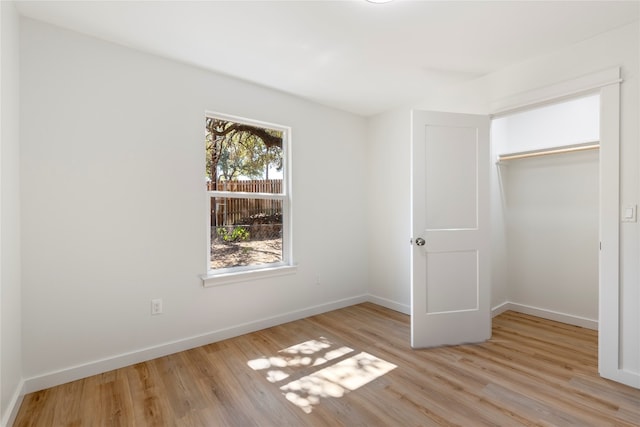 unfurnished bedroom featuring wood finished floors, baseboards, and a closet