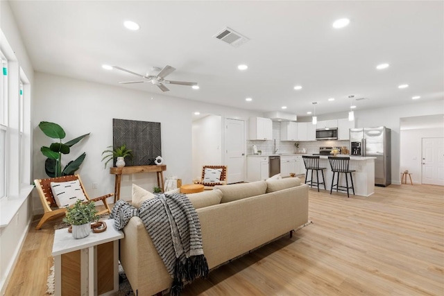 living room with light hardwood / wood-style floors and ceiling fan