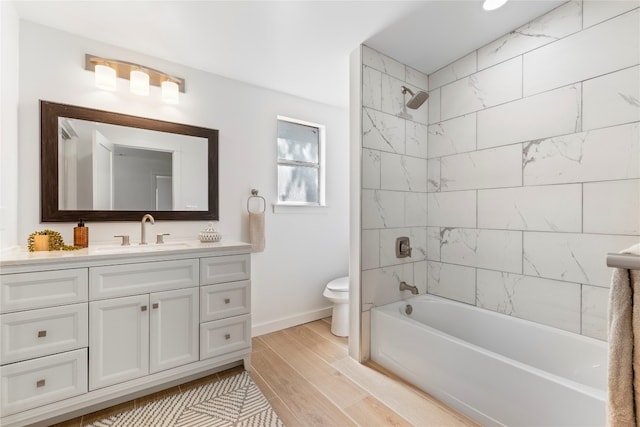 bathroom featuring baseboards, toilet, wood finished floors, vanity, and  shower combination