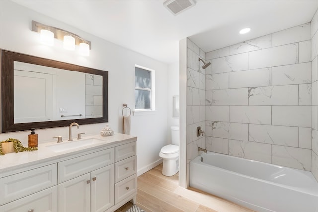 full bathroom with tiled shower / bath, vanity, toilet, and hardwood / wood-style floors