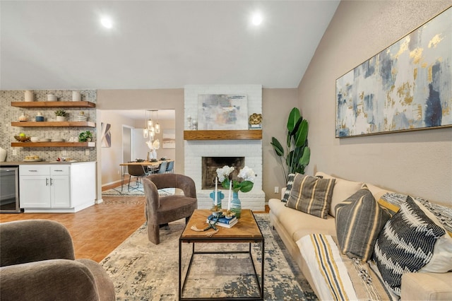 living room featuring light tile patterned flooring, a brick fireplace, beverage cooler, a notable chandelier, and lofted ceiling