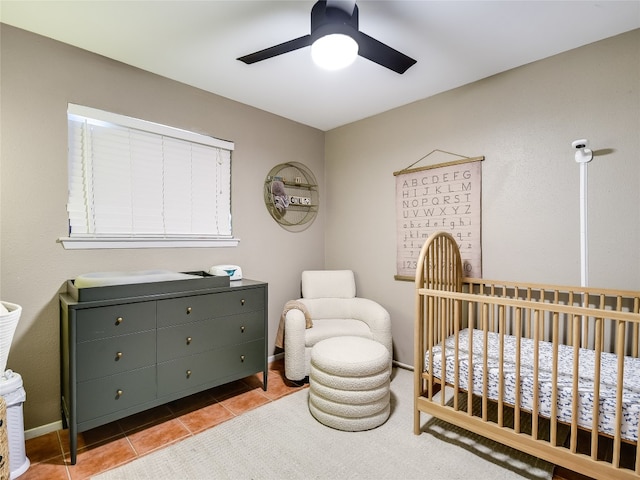 tiled bedroom with ceiling fan and a nursery area