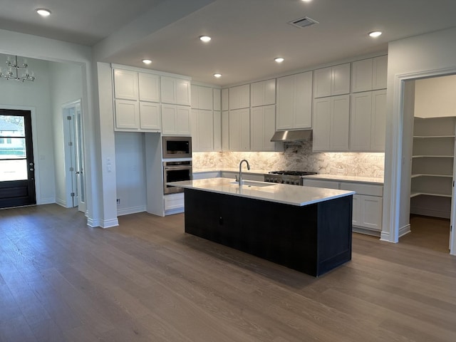 kitchen featuring white cabinetry, sink, a kitchen island with sink, appliances with stainless steel finishes, and light wood-type flooring