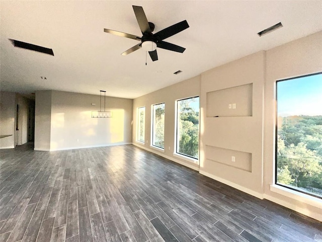 unfurnished living room with ceiling fan with notable chandelier and dark wood-type flooring