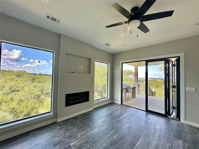 unfurnished living room featuring ceiling fan and a wealth of natural light