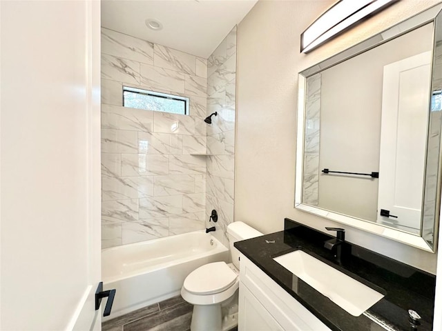 full bathroom featuring vanity, tiled shower / bath combo, and toilet