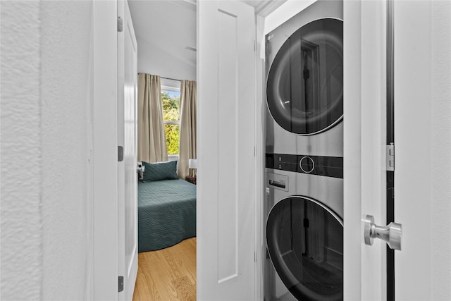 laundry room with laundry area, wood finished floors, and stacked washer and dryer