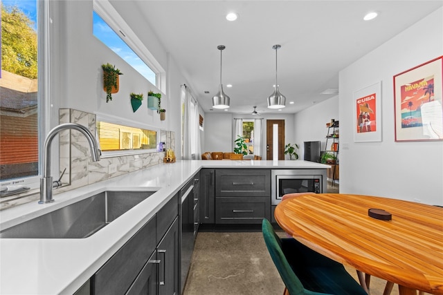 kitchen with sink, backsplash, kitchen peninsula, stainless steel appliances, and decorative light fixtures