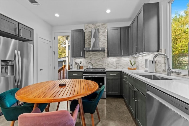 kitchen with visible vents, a sink, wall chimney exhaust hood, stainless steel appliances, and tasteful backsplash
