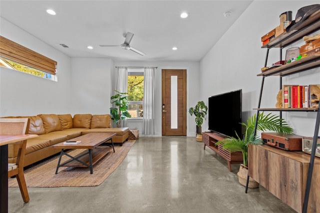 living room featuring ceiling fan and concrete flooring