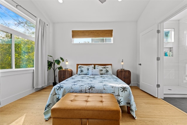 bedroom featuring vaulted ceiling, multiple windows, and light wood-type flooring