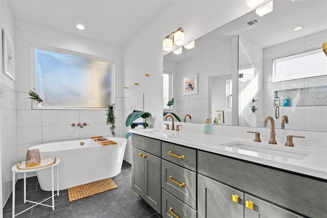 bathroom with tile walls, a freestanding bath, a stall shower, and a sink