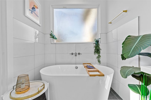 bathroom with tile walls, a bathtub, and tile patterned floors