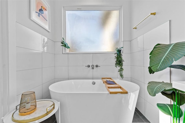 bathroom featuring tile patterned flooring, tile walls, and a freestanding tub