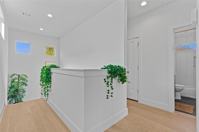 corridor with recessed lighting, attic access, baseboards, and light wood-style floors