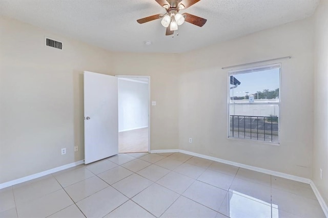 tiled empty room with ceiling fan and a textured ceiling