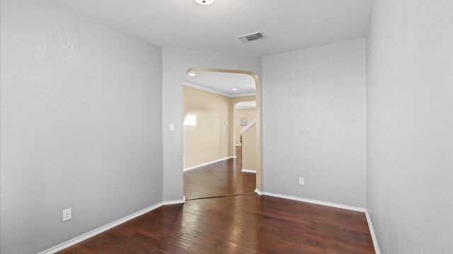 spare room featuring ornamental molding, a wall mounted air conditioner, and dark wood-type flooring