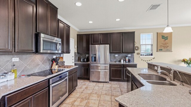 kitchen featuring appliances with stainless steel finishes, dark brown cabinets, decorative light fixtures, and sink