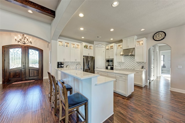 kitchen featuring appliances with stainless steel finishes, white cabinets, a kitchen island with sink, and dark hardwood / wood-style flooring