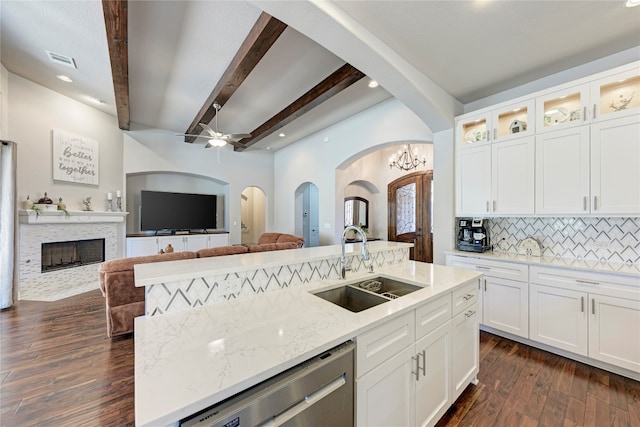 kitchen with a kitchen island with sink, beam ceiling, decorative backsplash, and white cabinetry