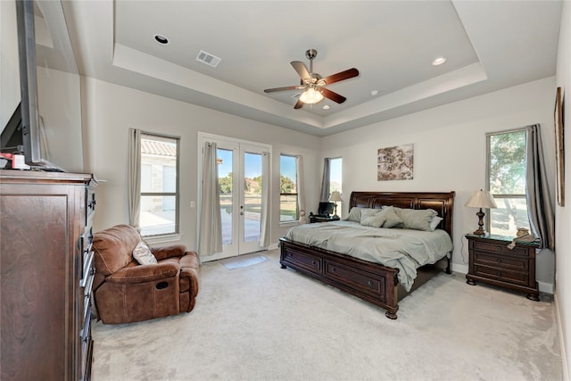 bedroom with ceiling fan, a raised ceiling, french doors, light colored carpet, and access to exterior