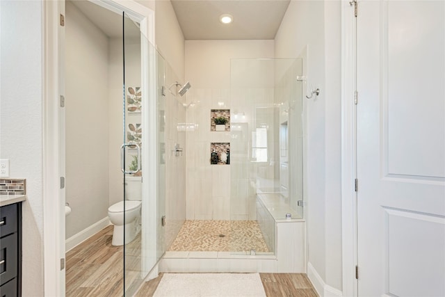 bathroom with a shower with door, hardwood / wood-style floors, vanity, and toilet