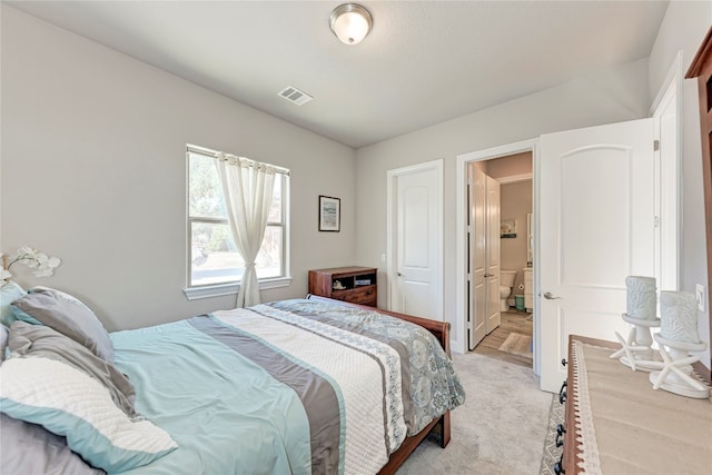 bedroom featuring ensuite bathroom and light colored carpet