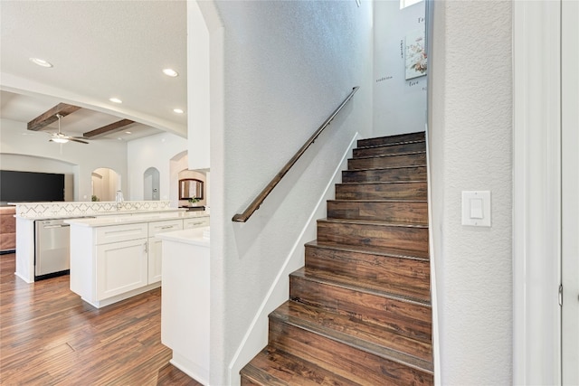 staircase featuring ceiling fan, hardwood / wood-style floors, and beam ceiling