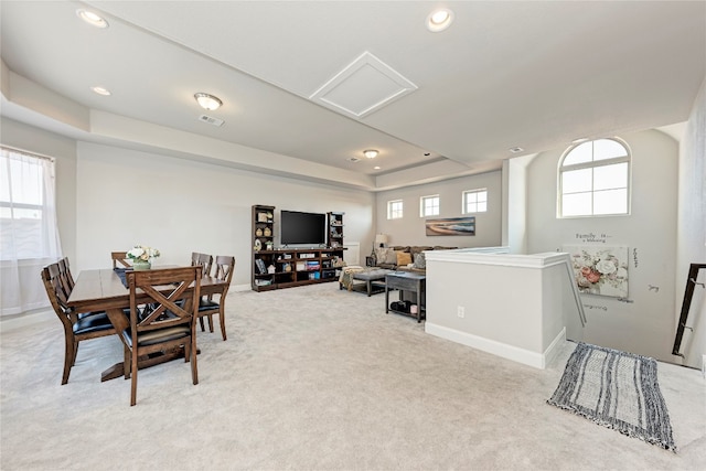 dining room with light carpet, a tray ceiling, and a healthy amount of sunlight