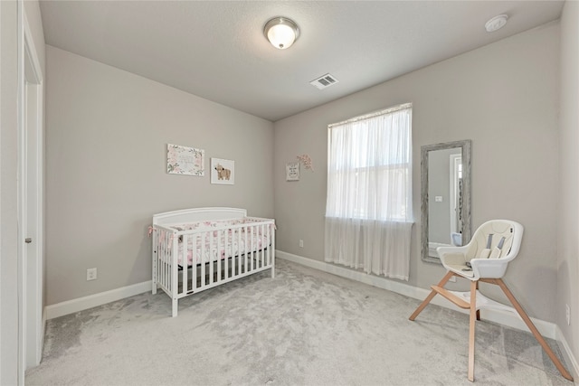 bedroom featuring a crib and light colored carpet