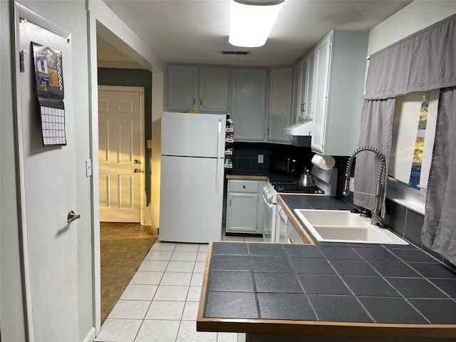 kitchen featuring white appliances, sink, tile countertops, gray cabinets, and light tile patterned floors