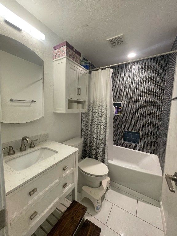 full bathroom with tile patterned flooring, shower / tub combo, toilet, vanity, and a textured ceiling