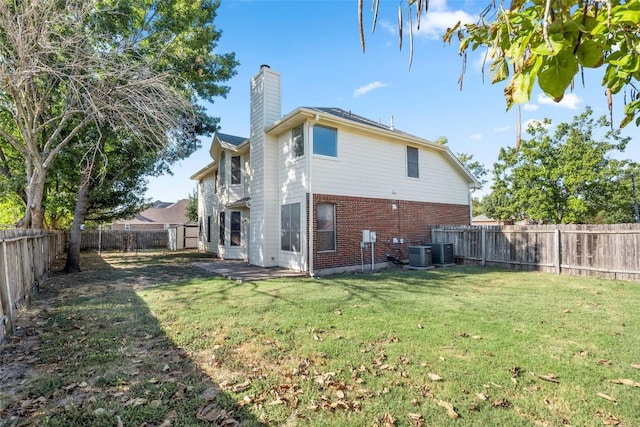 back of property featuring a lawn and central AC