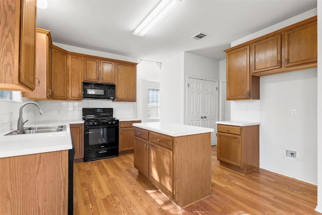 kitchen featuring black appliances, a kitchen island, light wood-type flooring, and sink