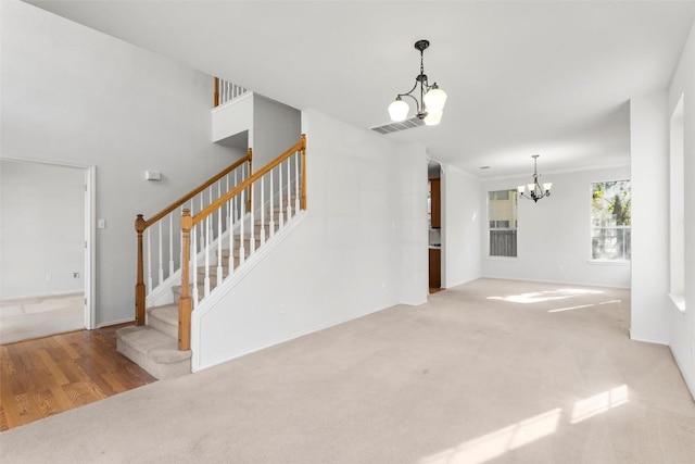 unfurnished living room with a notable chandelier, ornamental molding, and light carpet