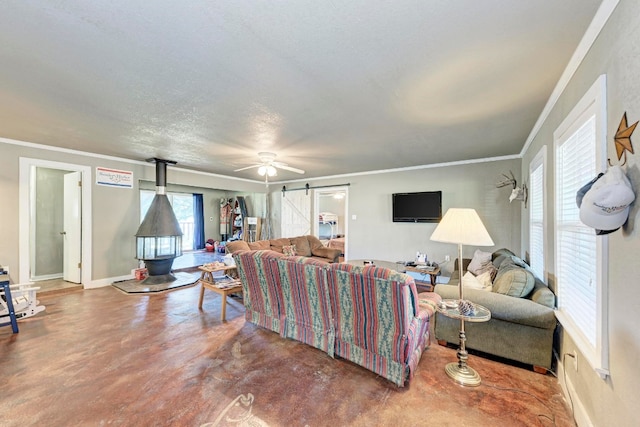 living room with a barn door, crown molding, a wood stove, and a healthy amount of sunlight