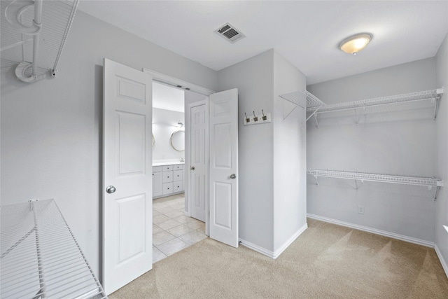 walk in closet with light carpet