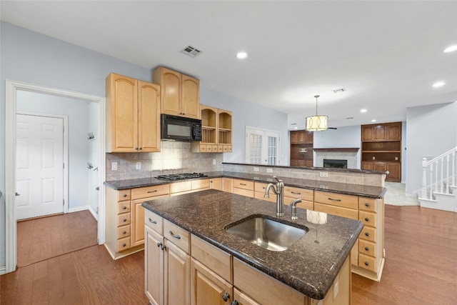 kitchen featuring hardwood / wood-style flooring, a kitchen island with sink, hanging light fixtures, and sink