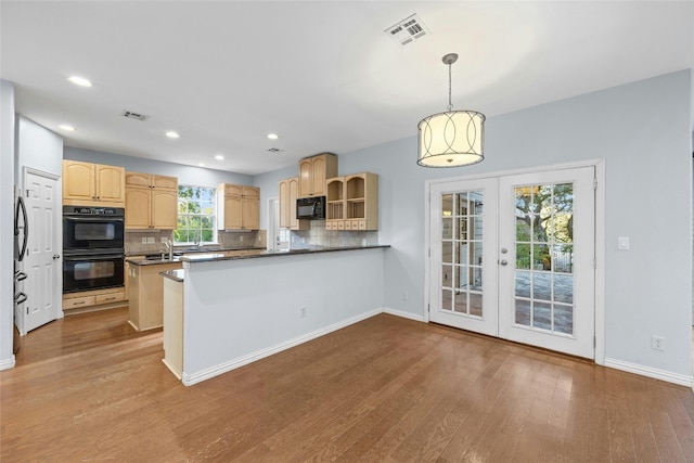 kitchen with hanging light fixtures, kitchen peninsula, french doors, black appliances, and light wood-type flooring