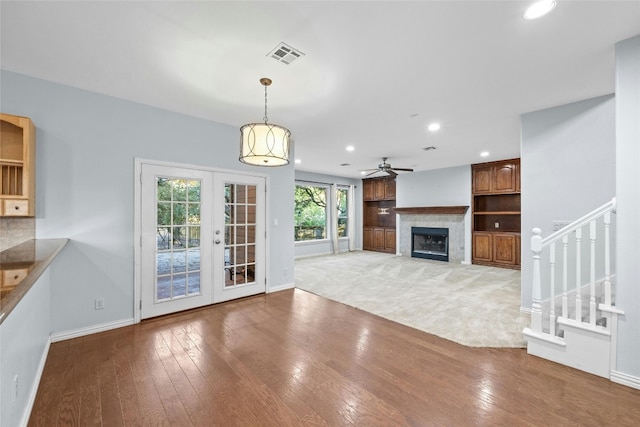 unfurnished living room with ceiling fan, hardwood / wood-style flooring, and french doors