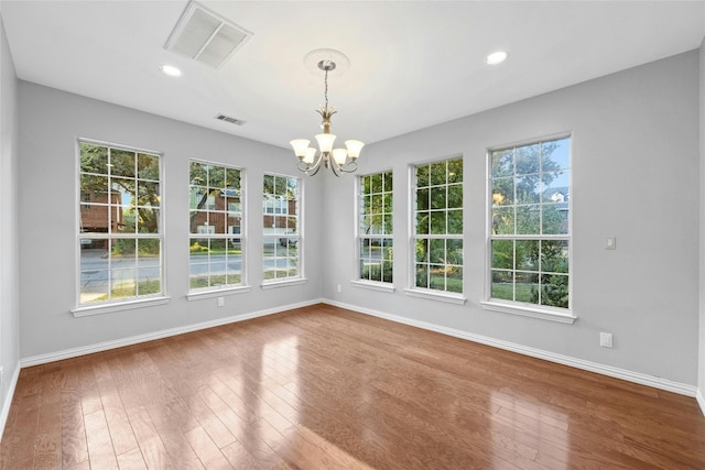 unfurnished dining area featuring a notable chandelier and hardwood / wood-style floors